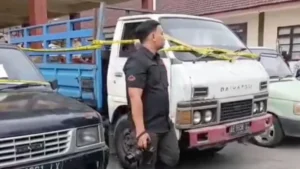 Truk bak biru dan pikap hitam dipasangi garis polisi sebagai barang bukti