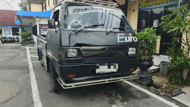 Pikap hitam dengan kaca depan retak dan kap penyok terparkir di halaman polres