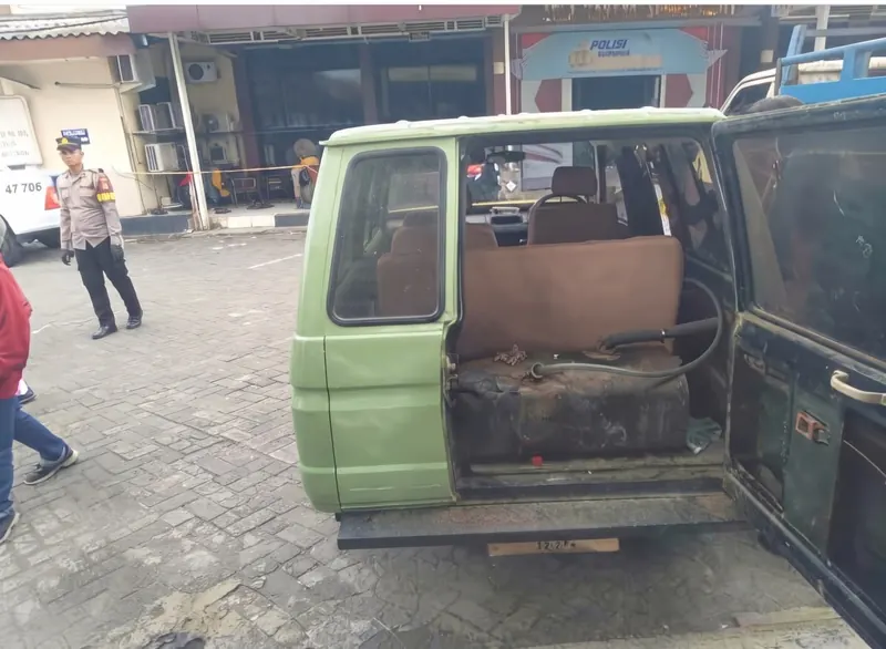 Tangki besar berselang di bagasi belakang mobil Kijang hijau di halaman kantor polisi